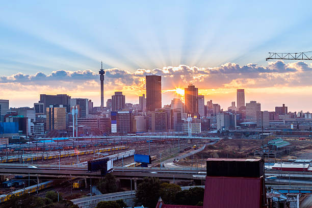 Johannesburg sunrise sunburst Johannesburg city sunrise panorama, with the sun rising between telkom tower and ponte city the prominent skyline skyscrapers in Johannesburg. Nelson Mandela bridge seen in the forefront and Park station and the railway line towards the left. The M1 overhead highway seen going accross. A crane stickin in from the left showing new construction and development. gauteng province photos stock pictures, royalty-free photos & images