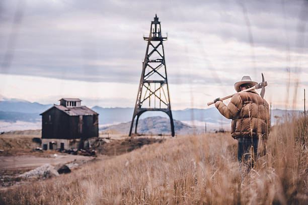 istock Cowboy walking through field with mountain range in background 501618117