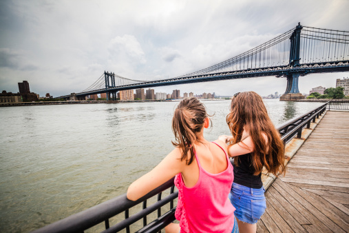 Two girls, sisters, looking to Manhattan Bridge under thunderstorm from Brooklyn, Brooklyn, New York 