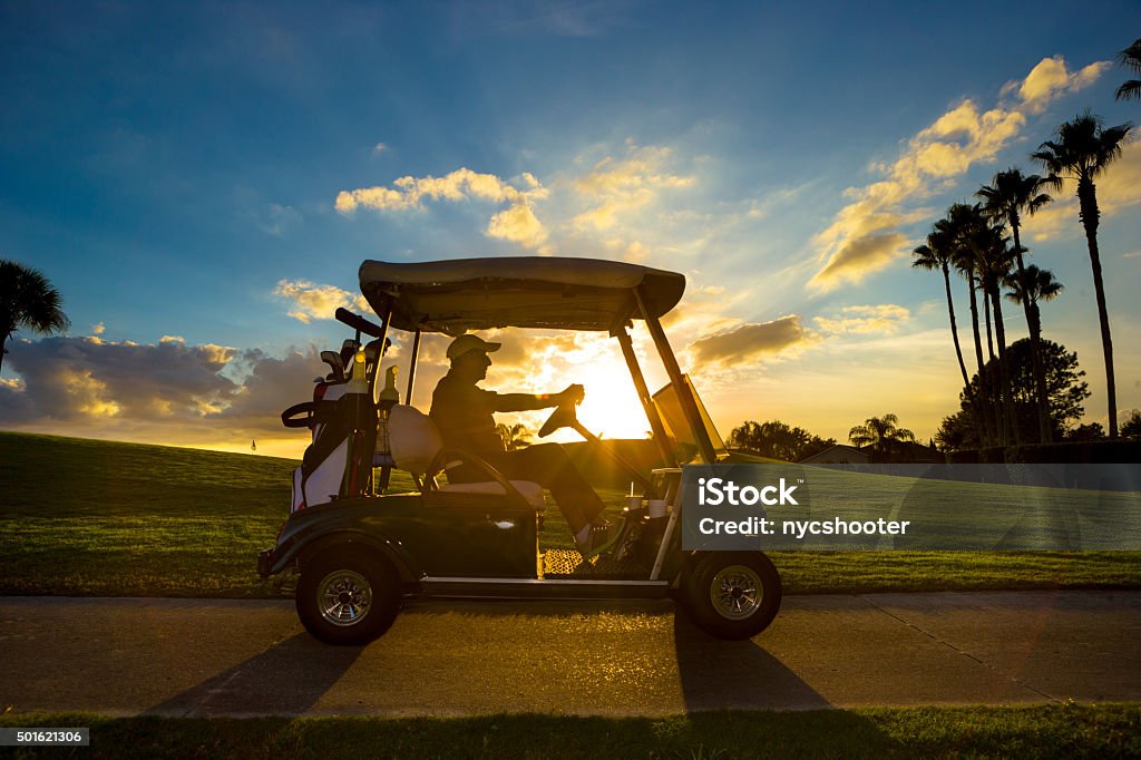 Senior golfer driving golf cart Senior man on golf course driving golf cart at sunrise Florida - US State Stock Photo