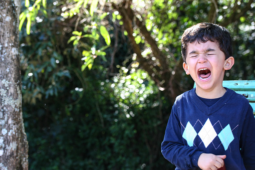 Boy crying while standing up in park