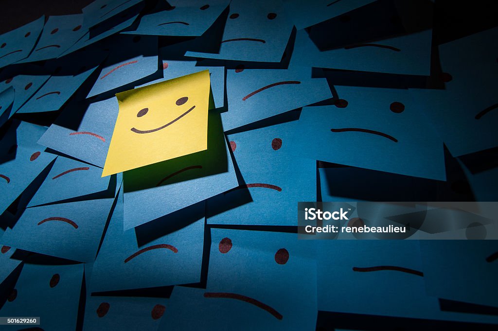 Positive and negative smiley Post it Yellow adhesive note stuck on the wall with funny smiley face Adhesive Note Stock Photo