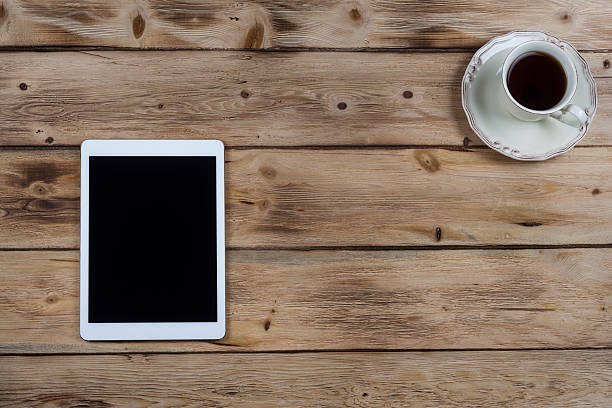istock Tablet PC with cup of coffee on old wooden desk 501630936