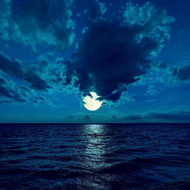 full moon in dramatic sky over water in night full moon in dramatic sky over water in night fantasy moonlight beach stock pictures, royalty-free photos & images