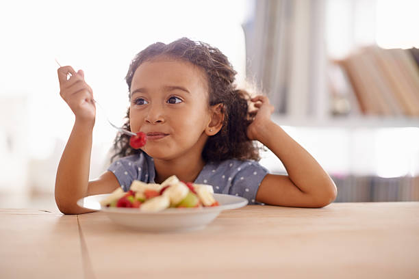 Everything good for a growing child Shot of a cute little girl eating fruit salad at a tablehttp://195.154.178.81/DATA/i_collage/pi/shoots/783539.jpg eating stock pictures, royalty-free photos & images