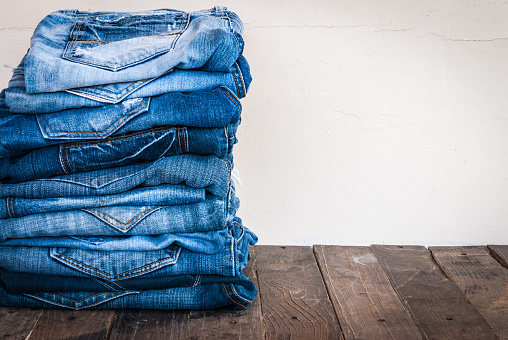 stack of various shades of blue jeans on old wood