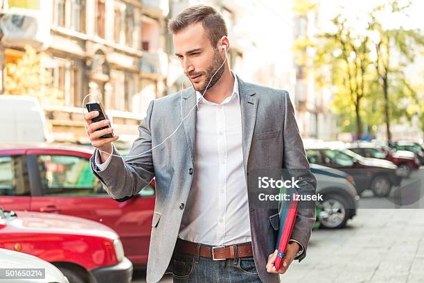 Businessman Wearing Earphone Talking On Smart Phone On The Street Stock Photo - Download Image Now