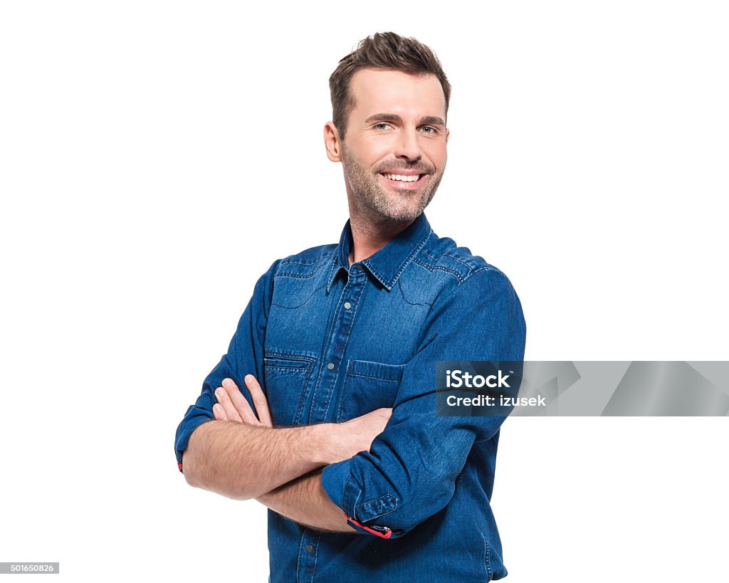 Portrait of happy man wearing jeans shirt Portrait of happy adult man wearing jeans shirt, standing against the white background with arms crossed, smiling at camera. Cut Out Stock Photo