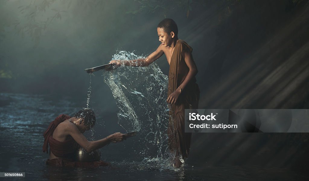 spree cool Novice playing water splash  on brook. Little monk of buddhism. Monk - Religious Occupation Stock Photo