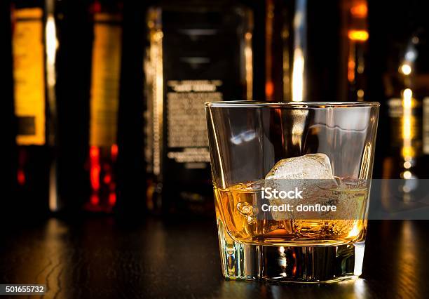 Whiskey Glass With Ice In Front Of Bottles Stock Photo - Download Image Now - Bottle, Alcohol - Drink, Whiskey