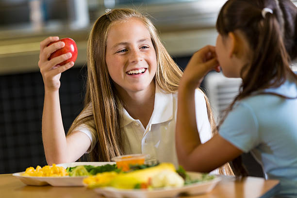 preteen ragazza mangiare sano pranzo in mensa di scuola con un amico - child food school children eating foto e immagini stock