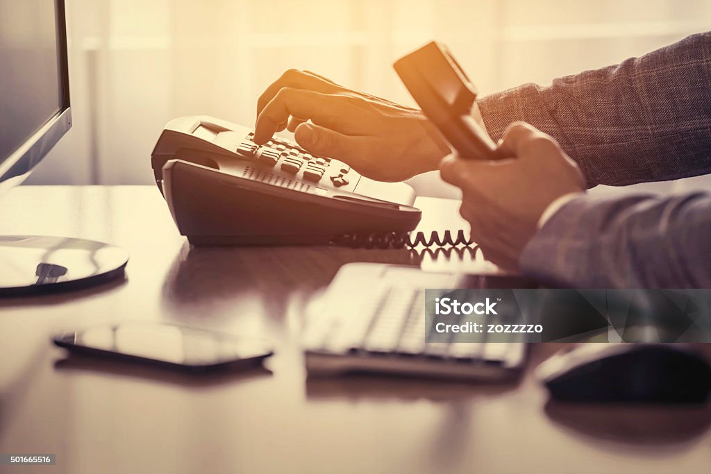 Dialing phone Businessman use the phone in the office, keyboard, mouse, mobile, and monitor detail in the background Telephone Stock Photo