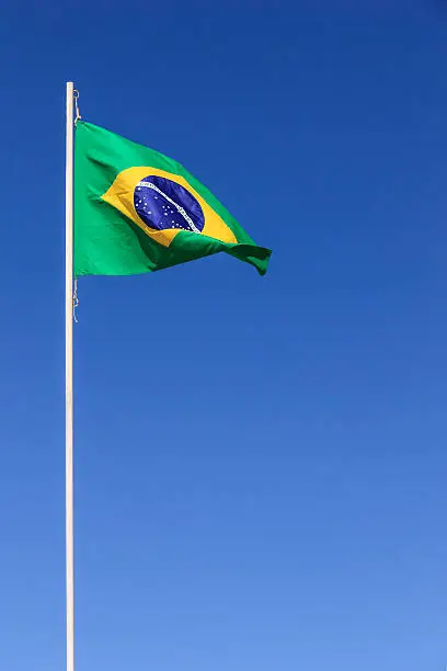Brazilian flag waving on top of a flagpole in a clear sky day