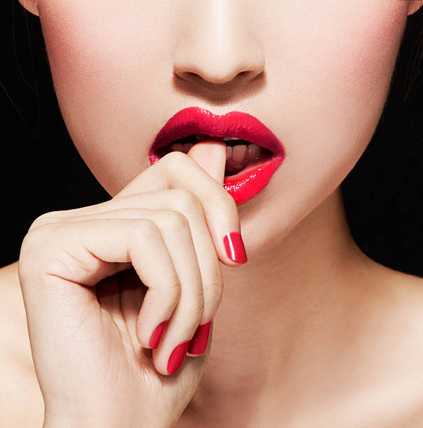 Closeup of woman biting nails or fingers.Red lips and manicure. stock photo
