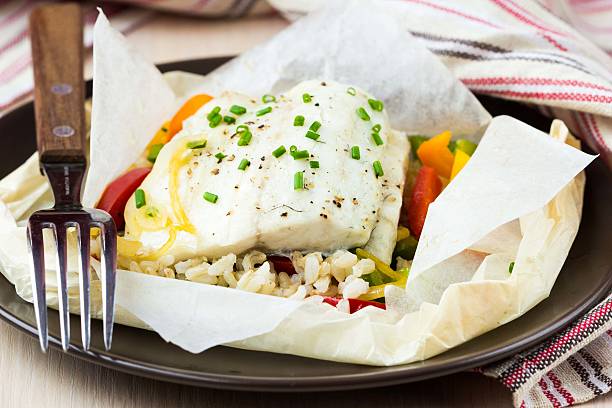 White fish fillet baked in paper, parchment with rice, pepper stock photo