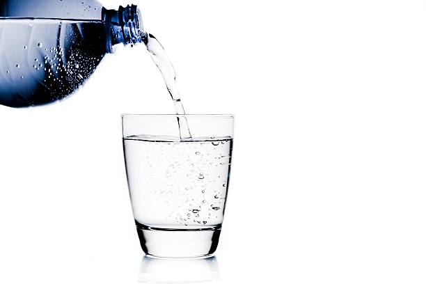 istock filling a glass with water trough blue bottle 501668644