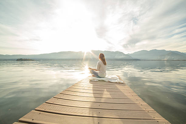 mujer joven relaja en el lago pier, los ejercicios de yoga - lake tranquil scene landscape zen like fotografías e imágenes de stock