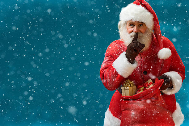 Santa Claus with keeping forefinger by his mouth stock photo