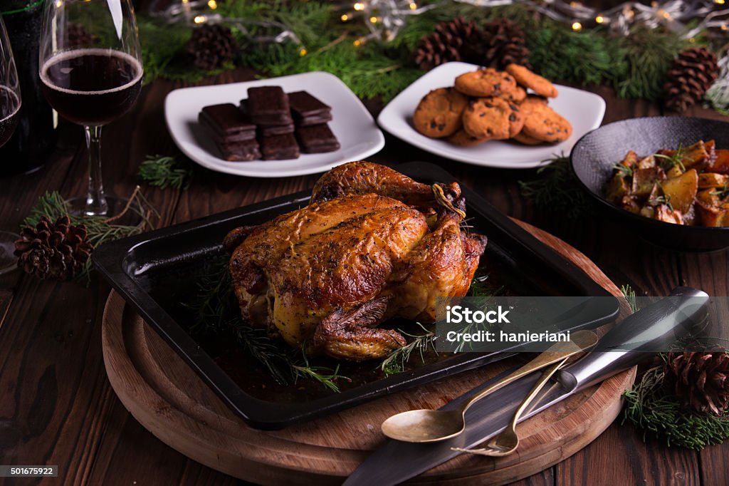 Christmas and new year's eve dinner: roasted whole chicken Christmas and new year's eve dinner: roasted whole chicken / turkey, sauteed cubed sweet potato, chocolate chip cookies, chocolate coated biscuits, and red wine 2015 Stock Photo