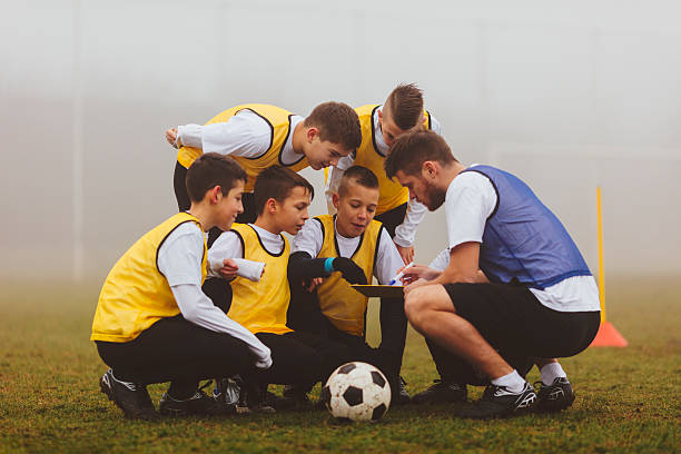 entrenador dar instrucciones a su equipo de fútbol de niños. - soccer teenager sport adolescence fotografías e imágenes de stock