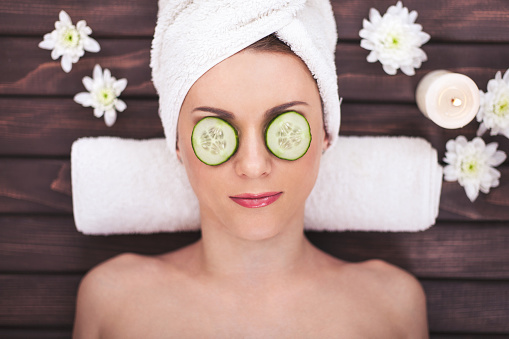 Beautiful girl at spa salon with cucumbers on eyes