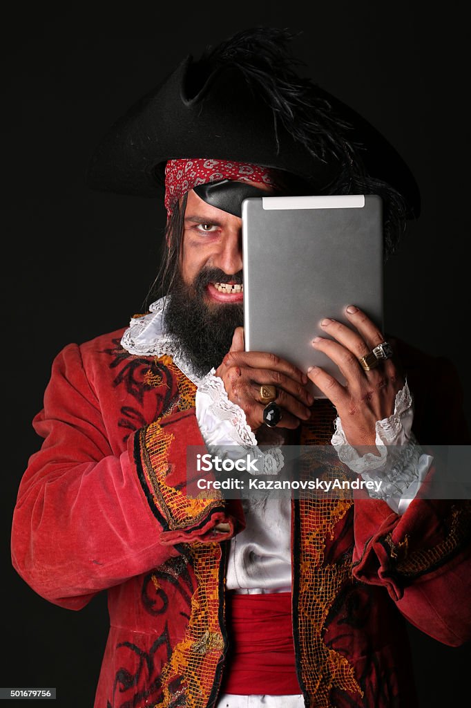 Portrait of man in a pirate costume with tablet Portrait of man in a pirate costume with hat and eye patch holding a tablet,  on black background Men Stock Photo