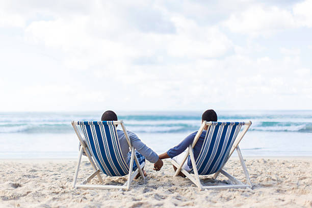 istock African couple sitting on beach chairs watching the water 501688759