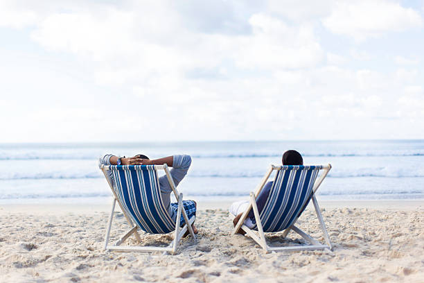 istock African couple sitting on beach chairs watching the water 501688761