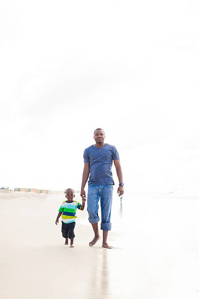 istock African father and son walking on the beach 501688765