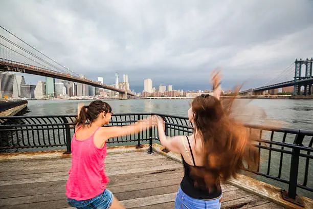 Two girls, sisters, dancing and playing at the waterfront, Brooklyn, New York 