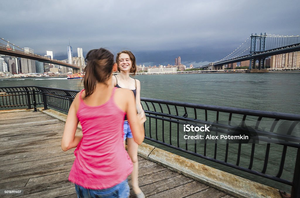 Two girls, sisters, looking to Manhattan under thunderstorm Two girls, sisters, looking to Manhattan under thunderstorm and if I were them I wouldn't laugh so hard. There's a storm coming and the sky is pretty dark, the blurred sister is hotter because of her tan and her pinky dress that looks pretty hot 10-11 Years Stock Photo