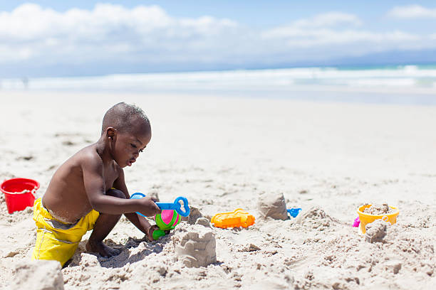 istock African boy building sandcastle at the beach 501692463