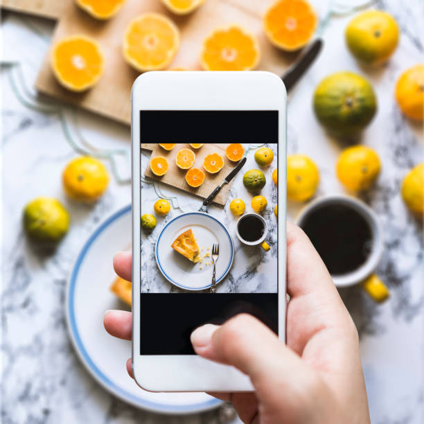 Share the moment Hand taking top view shot of table. Homemade cake, mandarine oranges and cup of coffee are on the table. kitchen counter photos stock pictures, royalty-free photos & images