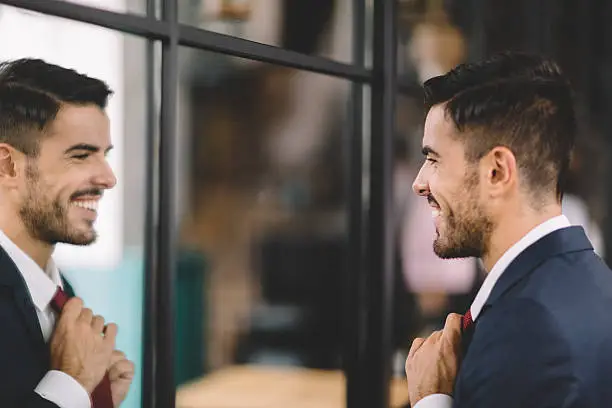 Smiling businessman fixing his necktie before going out