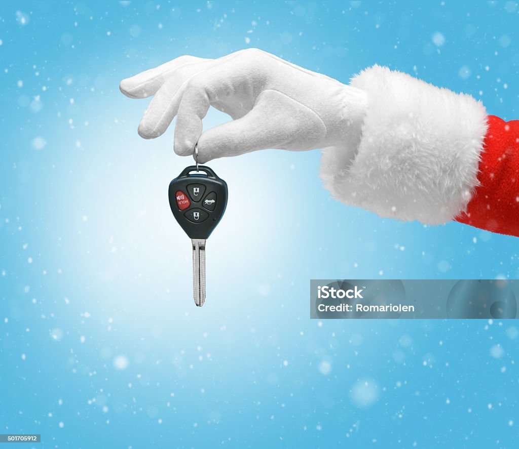 Hand in costume Santa Claus is holding car keys Hand in costume Santa Claus is holding car keys / studio shot of man's hand holding keys / Merry Christmas & New Year's Eve concept / Closeup on blurred blue background. Car Stock Photo