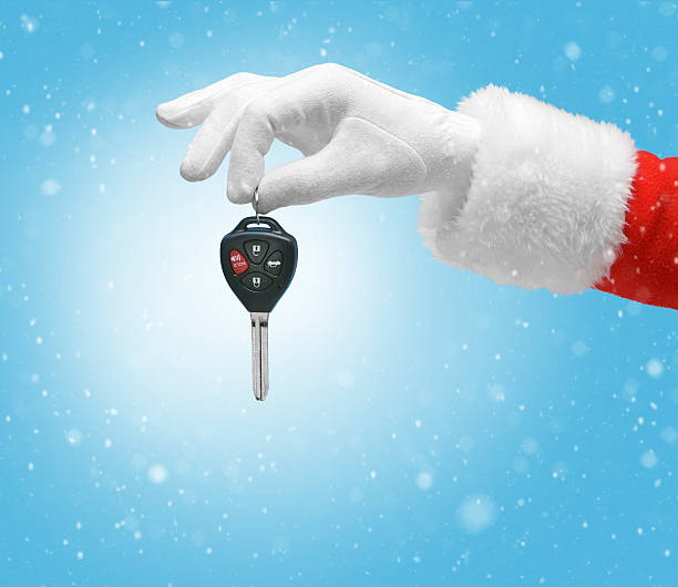 Hand in costume Santa Claus is holding car keys Hand in costume Santa Claus is holding car keys / studio shot of man's hand holding keys / Merry Christmas & New Year's Eve concept / Closeup on blurred blue background. car key photos stock pictures, royalty-free photos & images