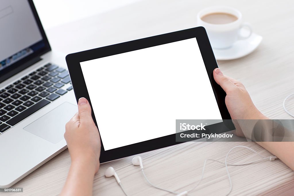 female hands holding a tablet with isolated screen female hands holding a tablet with isolated screen against the background of the table with a cup of coffee laptop and headphones Adult Stock Photo