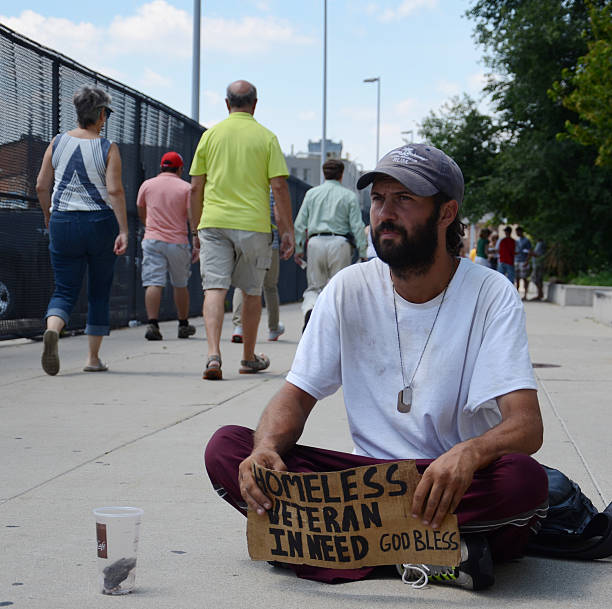 People walk past homeless veteran stock photo