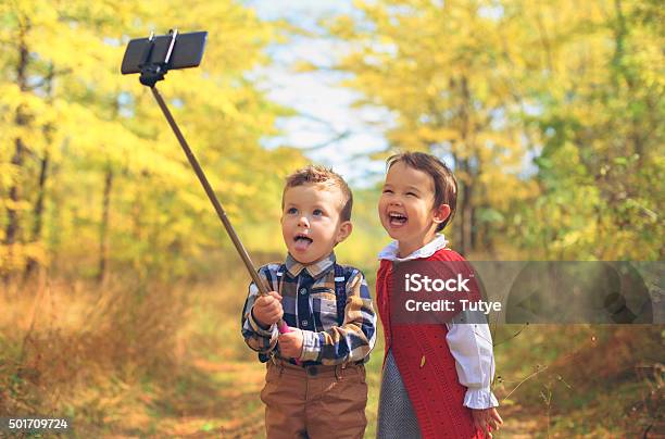 Dos Niños Kids Tomando Autofoto Foto de stock y más banco de imágenes de 2015 - 2015, A la moda, Aire libre