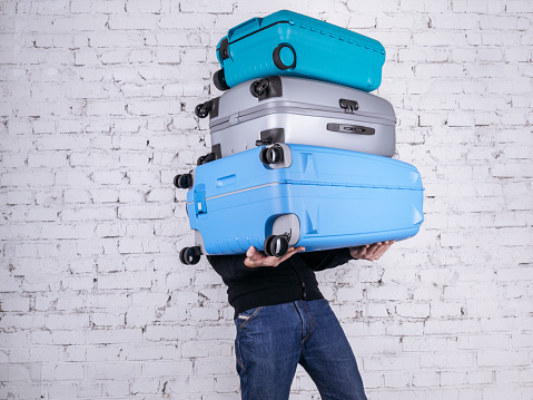 Man holding three heavy suitcases in hand. Travel light.