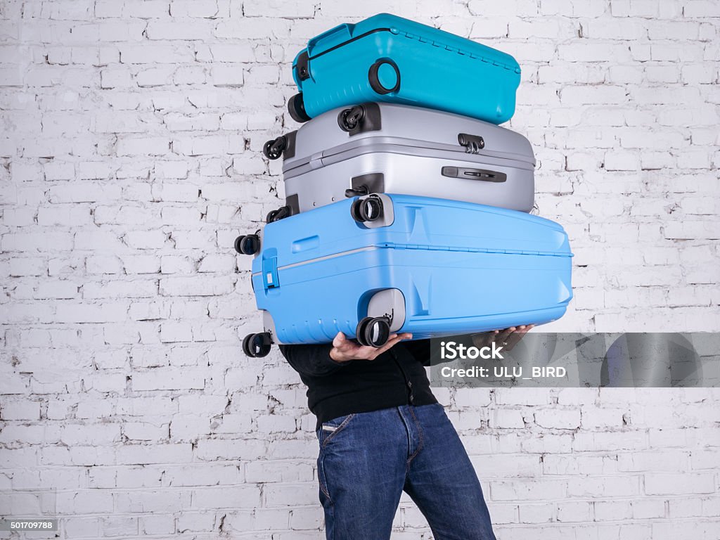 The man with the suitcases Man holding three heavy suitcases in hand. Travel light. Luggage Stock Photo