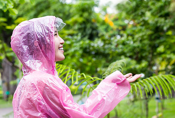 mujer asiática en rosa gabardina comprobación de lluvia - checking for rain fotografías e imágenes de stock