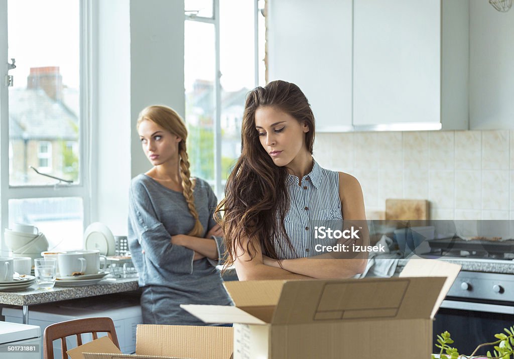 Conflict between roommates Two girls having quarrel at home, giving up the cohabitation. Cardboard boxes on the table. Arguing Stock Photo