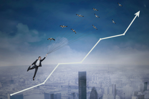 Young businesswoman flying with birds over upward arrow symbolizing growing business