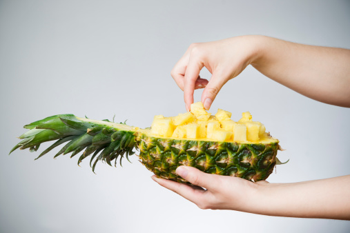Pineapple in female hands on gray background. Weight loss, diet