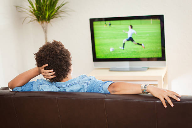 persone guardare la televisione broadcasting calcio sport, rilassante sul divano di casa - rear view women back back of head foto e immagini stock