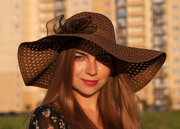 девочка в коричневая плетеная шляпа на фоне высоких дома - affectionate desire beauty brown стоковые фото и изображения