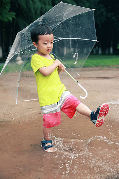 かわいい公園で遊ぶお子様 - rain drenched one person standing ストックフォトと画像