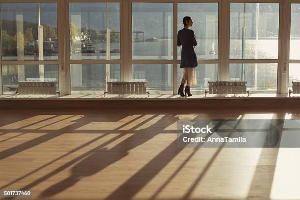 Woman Standing Near Large Window And Looking To Sunset Stock Photo - Download Image Now