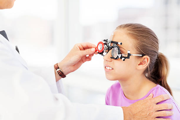 Optician Examining Girl's Vision In Clinic Mature optician examining girl's vision in clinic. Horizontal shot. Messbrille stock pictures, royalty-free photos & images